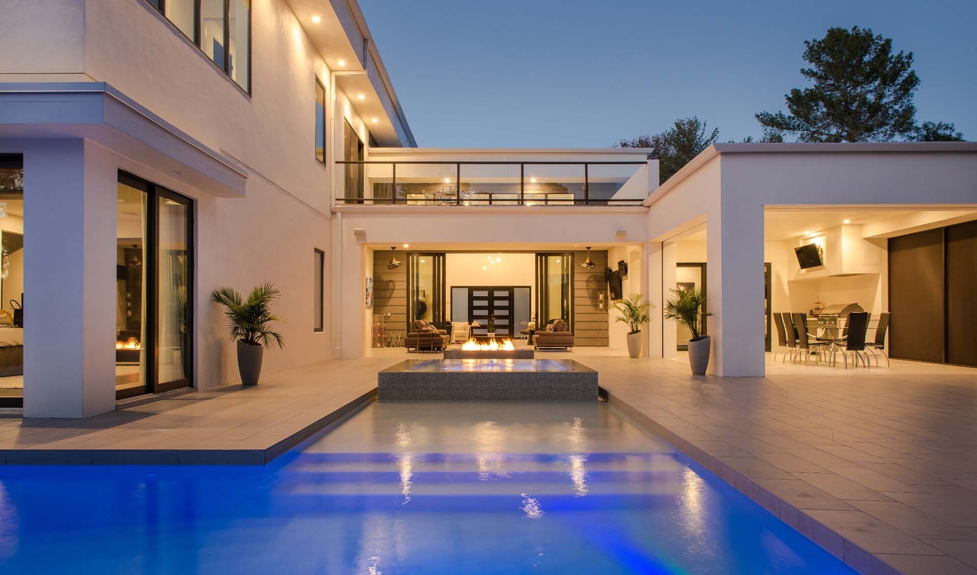 Outside view of a modern house with a big pool and fireplace